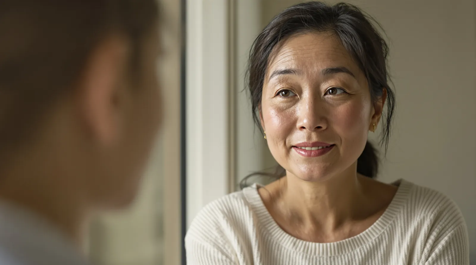 A woman in her forties with light freckles and even skin tone smiles softly